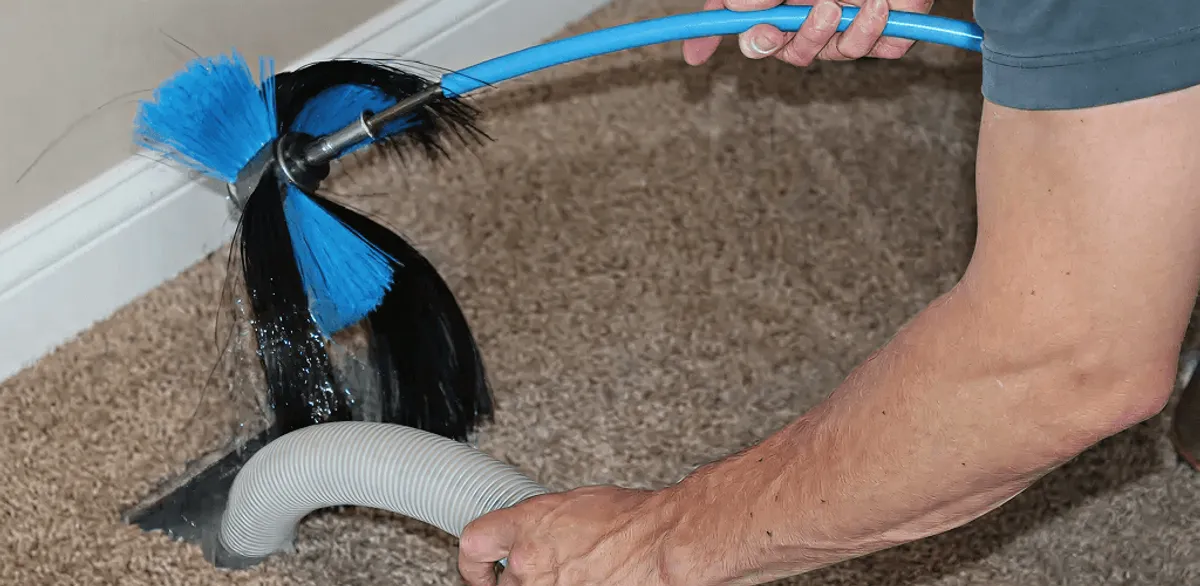 Dryer vent cleaning technician brushing lint from a vent line in Irvine, CA
