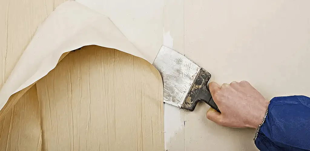 Handyman removing wallpaper with a scraper for wall preparation in Irvine, CA