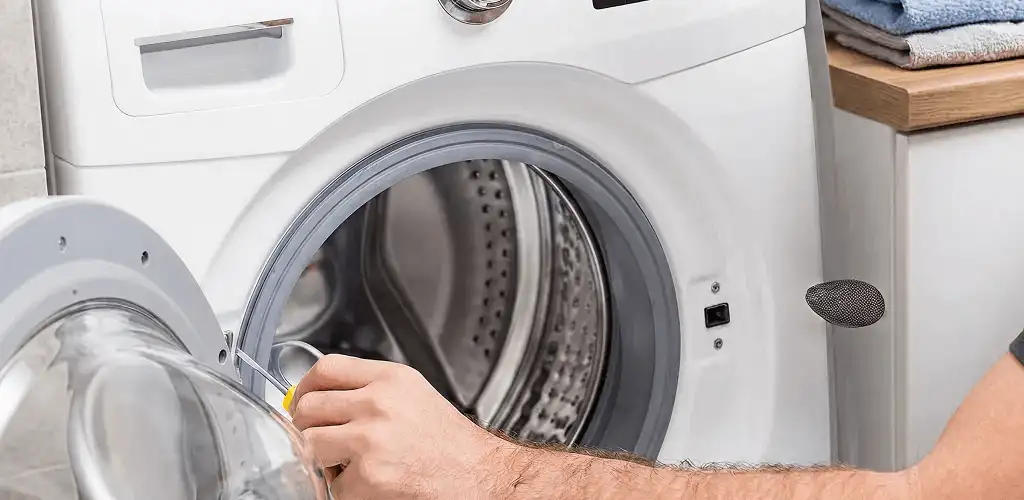 Handyman repairing a front-load washing machine and inspecting the drum in Irvine, CA