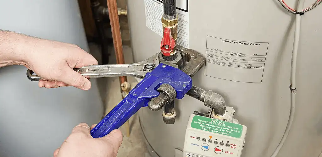Water heater repair technician tightening the shutoff valve and supply line in Irvine, CA